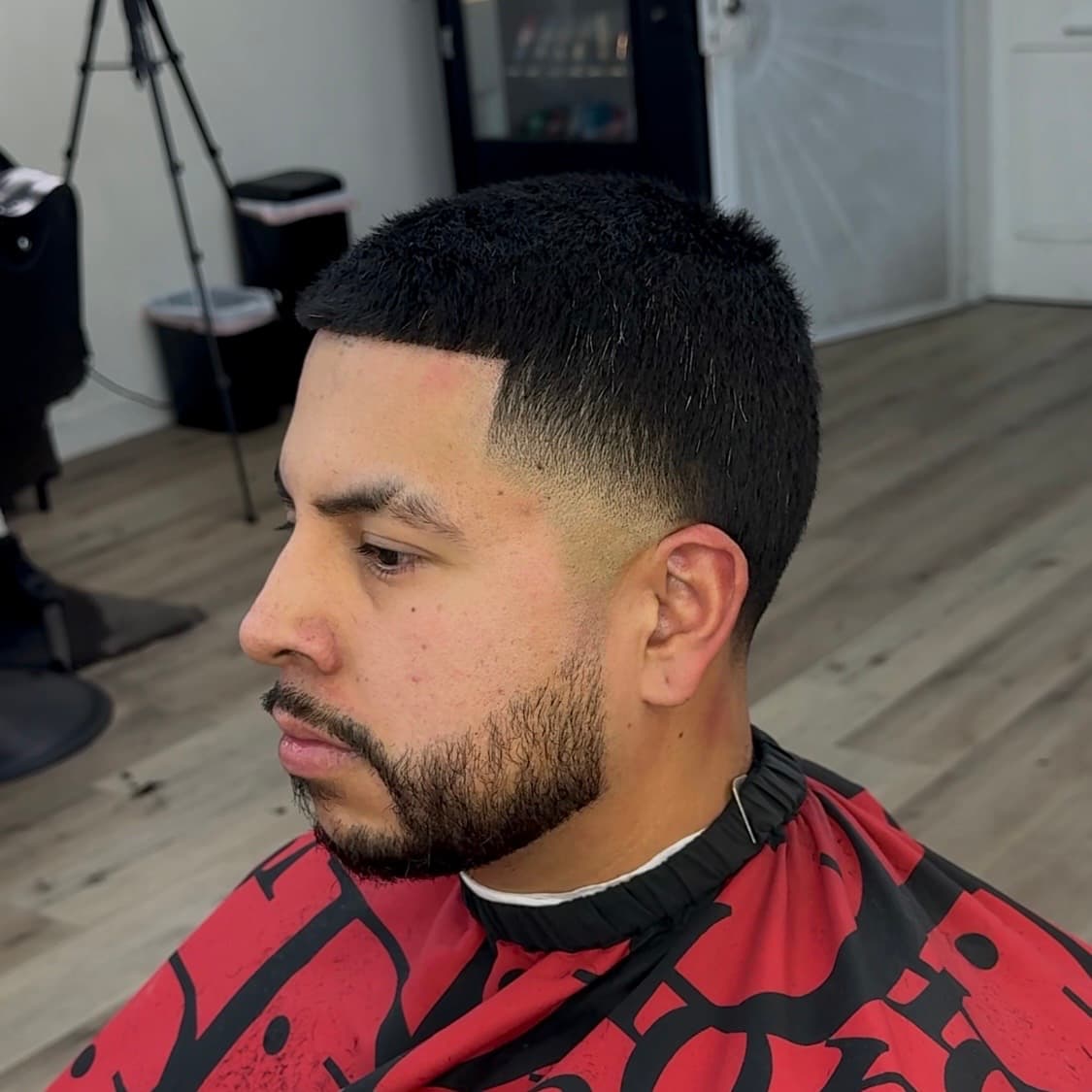 Side profile of a man with a fresh fade haircut, sharp lineup, and groomed beard.